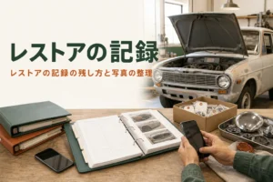 レストアの記録の残し方を紹介する記事のアイキャッチ。作業台のバインダーと部品の箱、奥の古い車